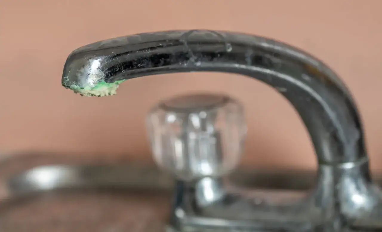 Robinet entartré, avec des dépôts verts et blancs. Il est temps de dissoudre le calcaire pour retrouver un débit normal.