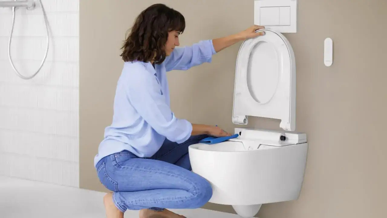 Une femme nettoie le nouveau siège de toilette. C'est le moment de changer abattant wc pour un modèle plus moderne et hygiénique.