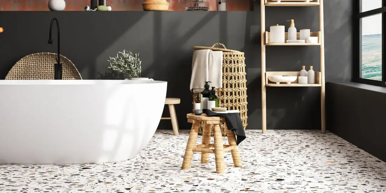 Le sol de salle de bain en terrazzo multicolore complète la baignoire blanche, le tabouret en bois et le panier en osier.