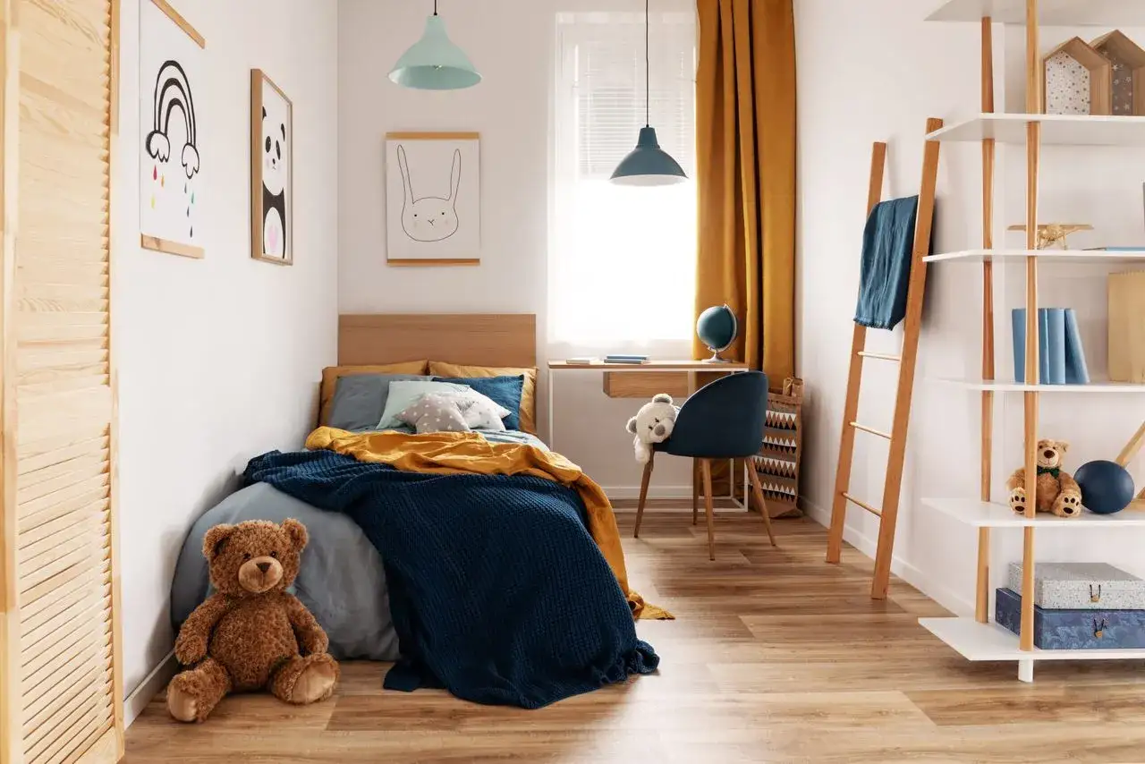 Chambre d'enfant douillette avec lit bleu et jaune, ours en peluche et affiches. Le chauffage de la chambre b&eacute;b&eacute; est assur&eacute; par un radiateur discret.