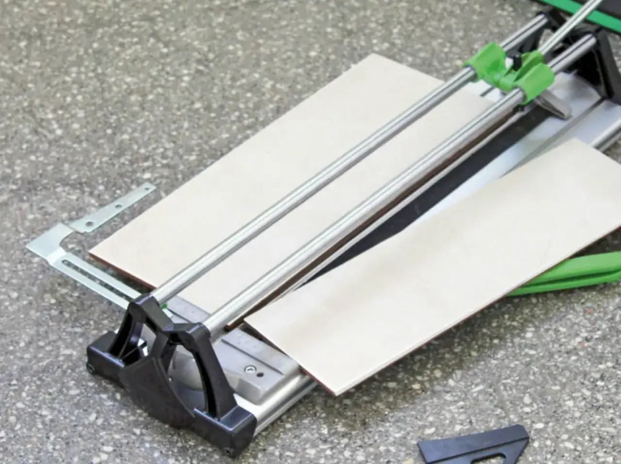 Machine de d&eacute;coupe de carrelage avec deux carreaux pr&ecirc;ts &agrave; &ecirc;tre coup&eacute;s.