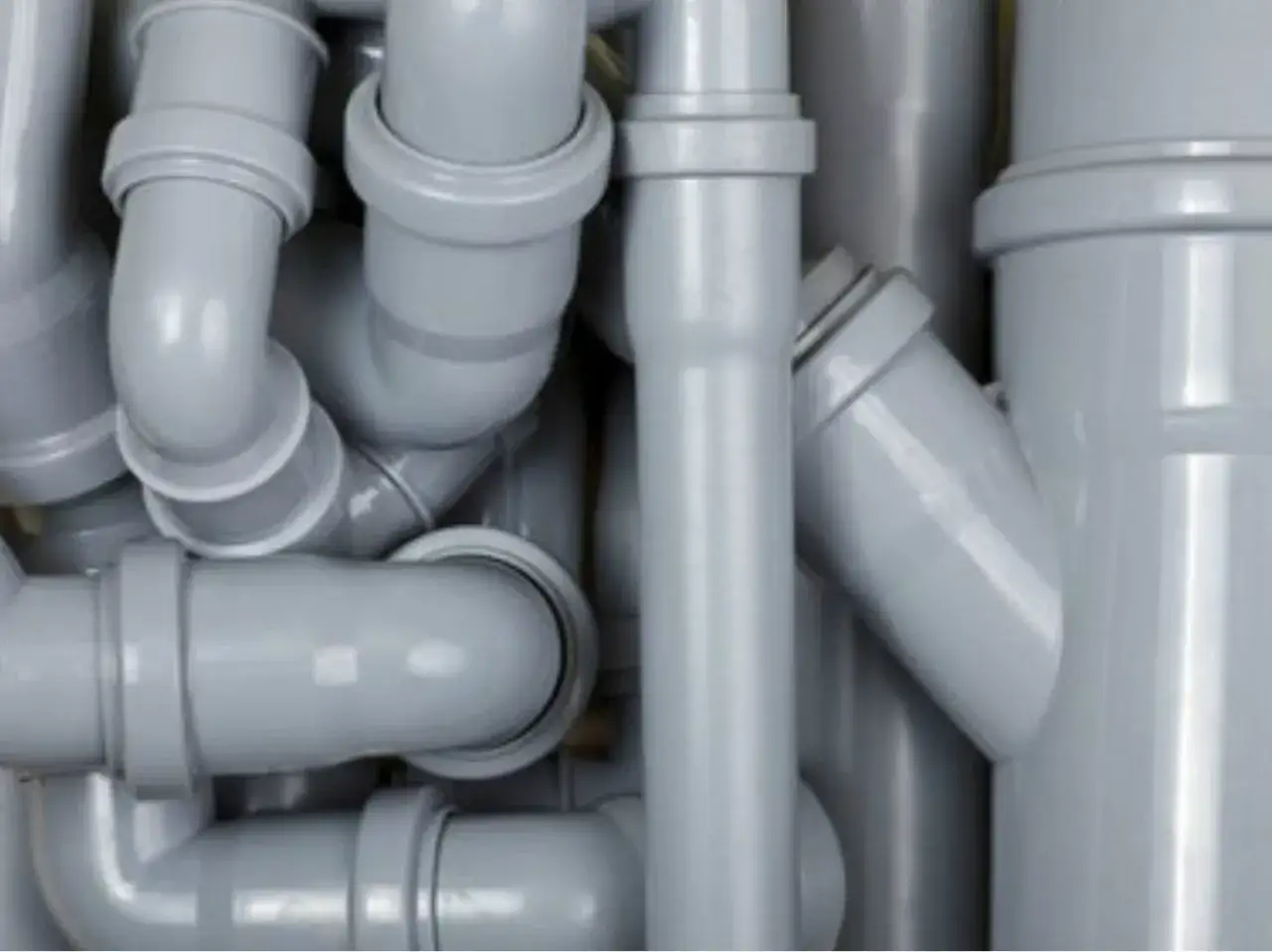 Un enchevêtrement de tuyaux en plastique gris, formant un réseau complexe pour l'évacuation.