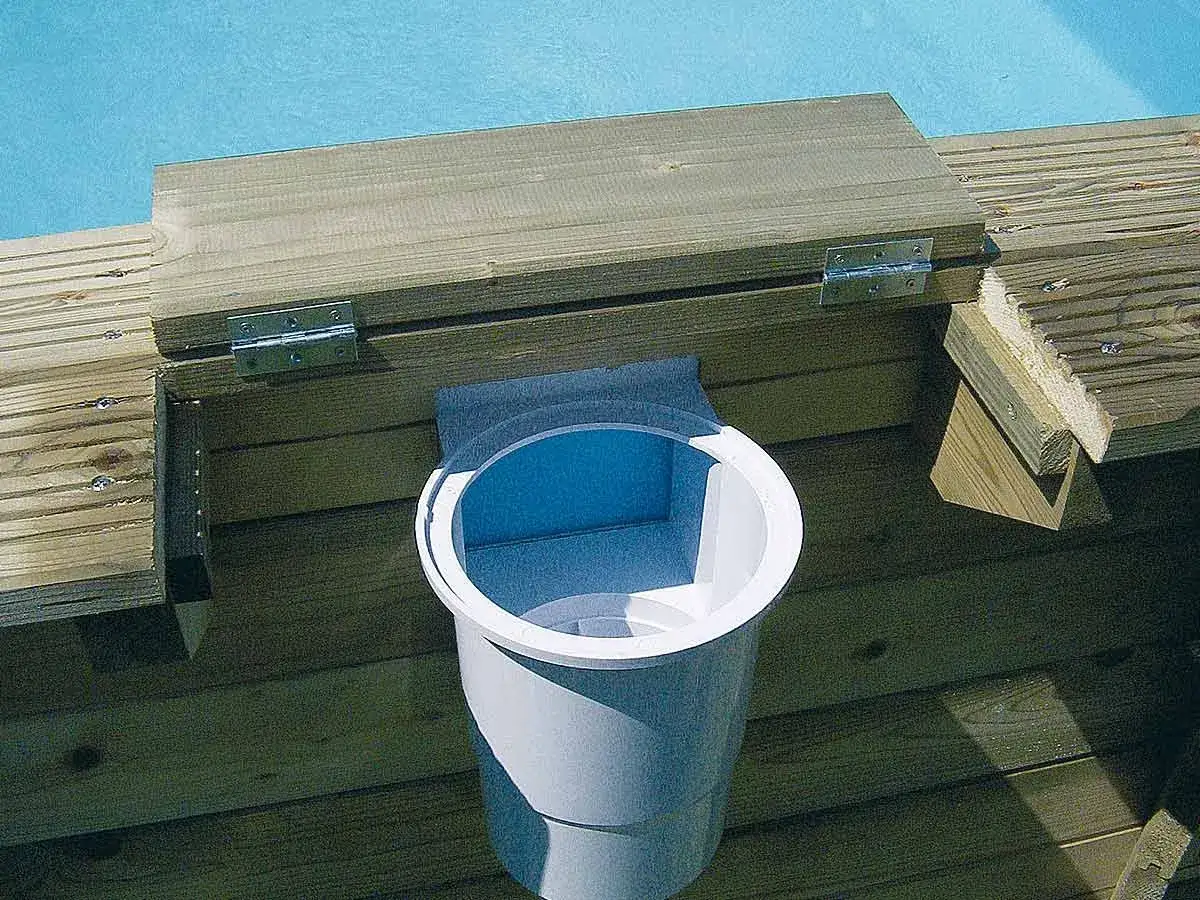 Détail du branchement skimmer piscine hors sol sur une structure en bois. Le skimmer blanc est visible, fixé à la paroi.