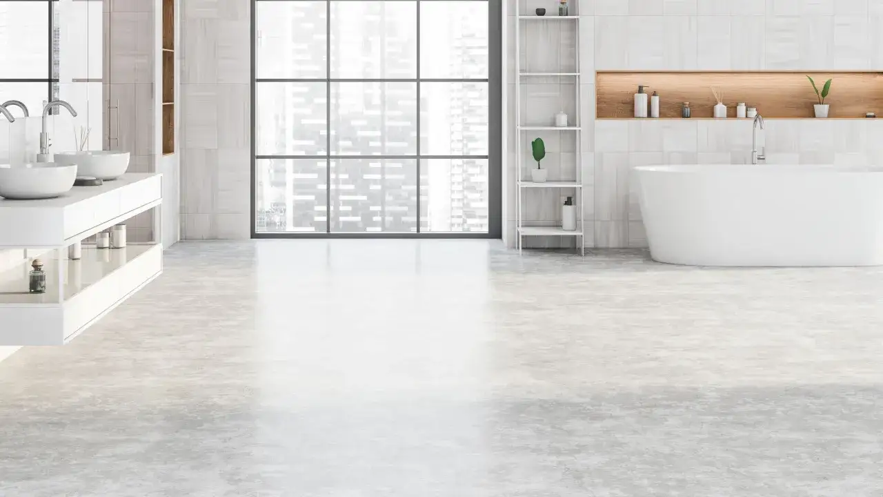 Sol de salle de bain en béton ciré, reflétant la lumière d'une grande fenêtre urbaine.