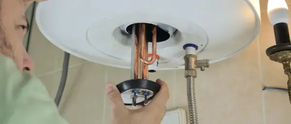 Un technicien manipule la résistance chauffante d'un chauffe-eau.