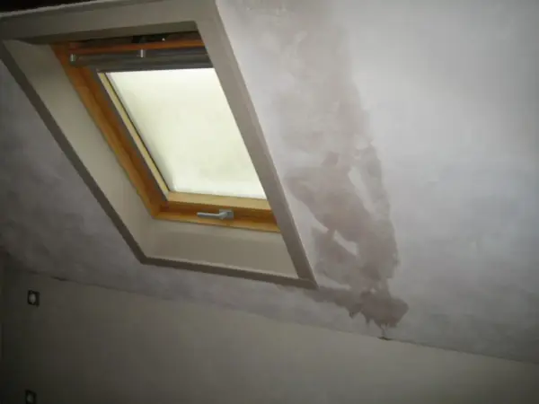 Gouttes d'eau sur le mur d'une maison non chauffée, près d'une fenêtre de toit. La condensation s'accumule et coule.