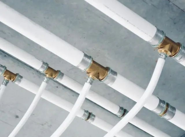 Système de tuyauterie blanche avec raccords en laiton, une installation multicouche complexe sous un plafond en béton.