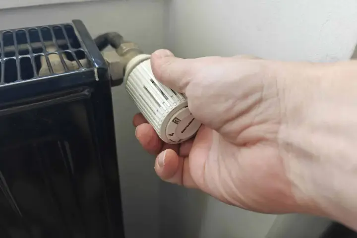 Main tenant ajuste le thermostat pour savoir quand éteindre le chauffage.
