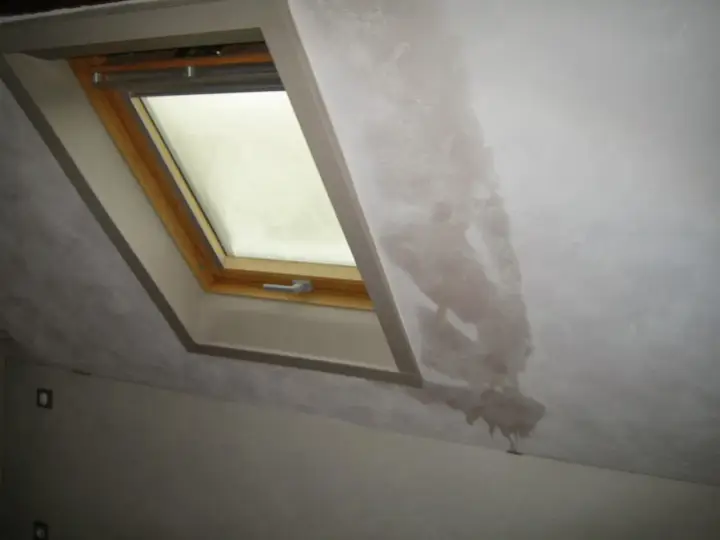 Gouttes d'eau sur le mur d'une maison non chauffée, près d'une fenêtre de toit. La condensation s'accumule et coule.