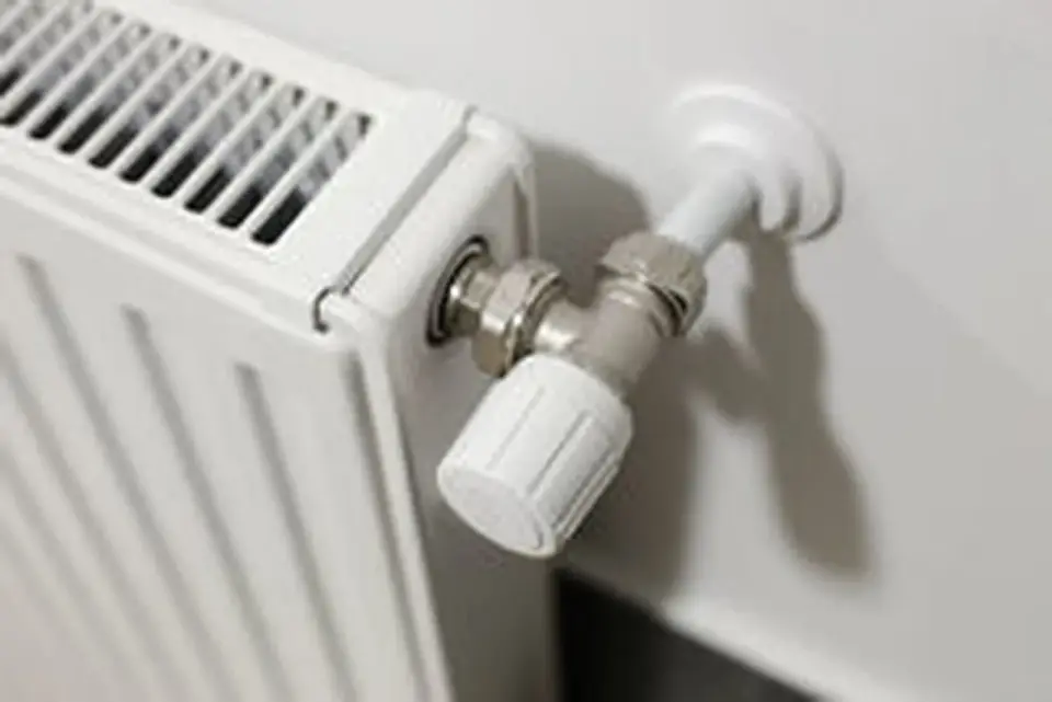 Détail d'un radiateur blanc avec sa vanne thermostatique. Idéal pour planifier le déplacement d'un radiateur électrique.